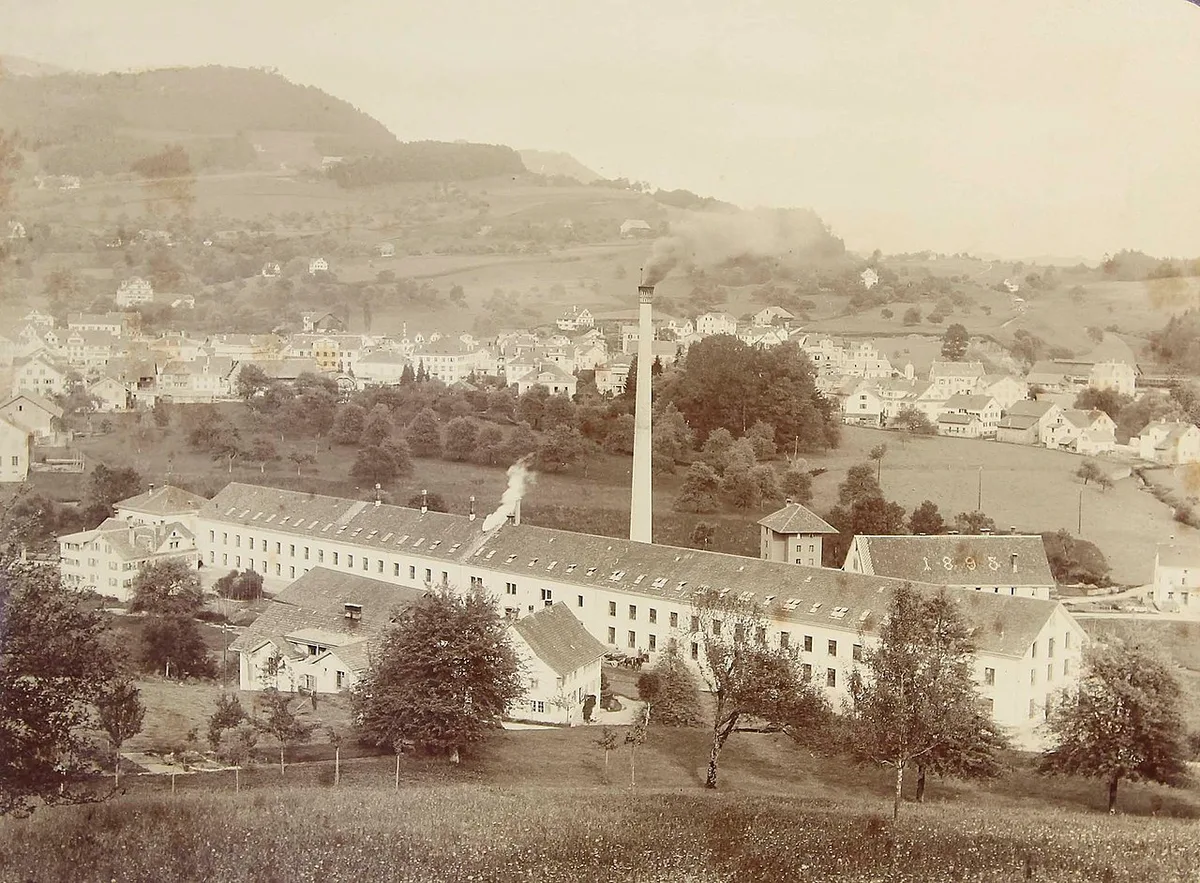 Eine Aufnahme der Weberei um 1900. Man sieht ein altes Fabrikgebäude.